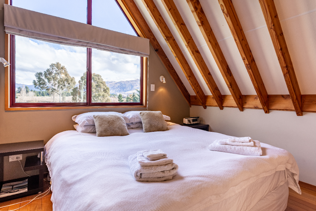 Master bedroom with exposed beam ceiling and king bed